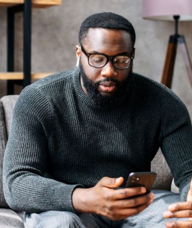 A man using his phone for an online addiction therapy session