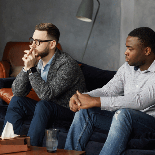 Two men in a therapy session with an unseen therapist