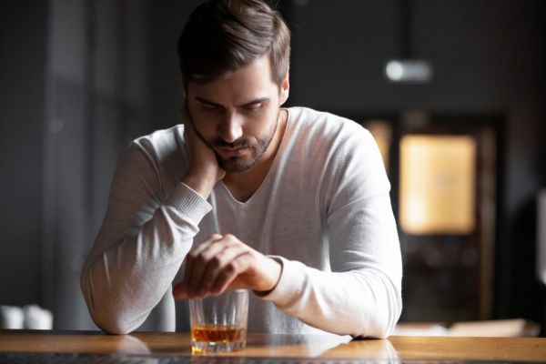 Sullen young man with a fourth-glass of alcohol