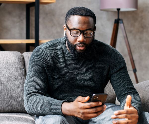 A man using his phone for an online addiction therapy session