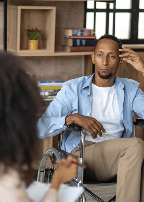 A man in a wheelchair listens to a therapist explains ways to pay for drug rehab