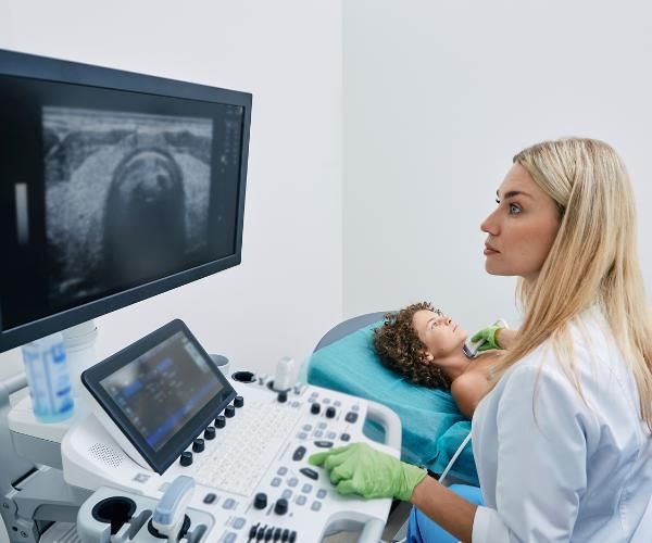 An ultrasound tech using a wand to get images of a patient's thyroid