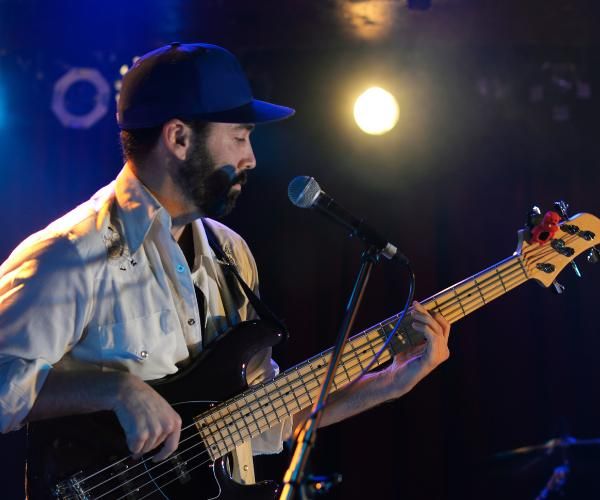 A solo guitarist standing at a mic and playing at a dimly lit venue