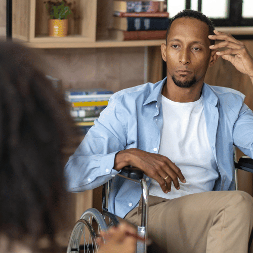 A man in a wheelchair listens as a therapist explains how to pay for alcohol addiction rehab without insurance