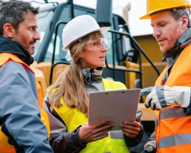 A woman construction worker and two male workers consult