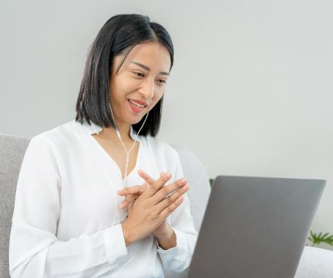 Young woman sitting on a couch with a laptop during virtual therapy