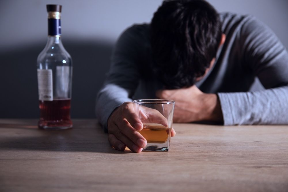 Drunk man with alcohol bottle wondering what is alcohol addiction