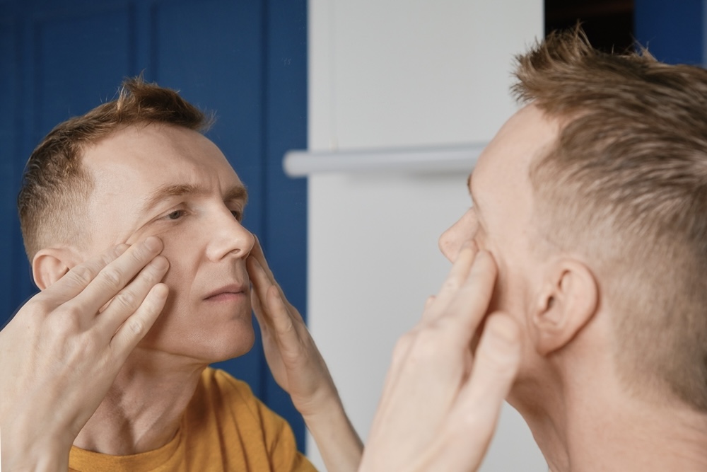 Man looking at the mirror checking for pinpoint pupils from opioid use