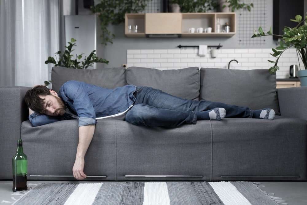Drunk man sleeping on the sofa after a night of drinking
